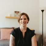 Image of 40 year old white woman with cropped hair and large grey couch in background